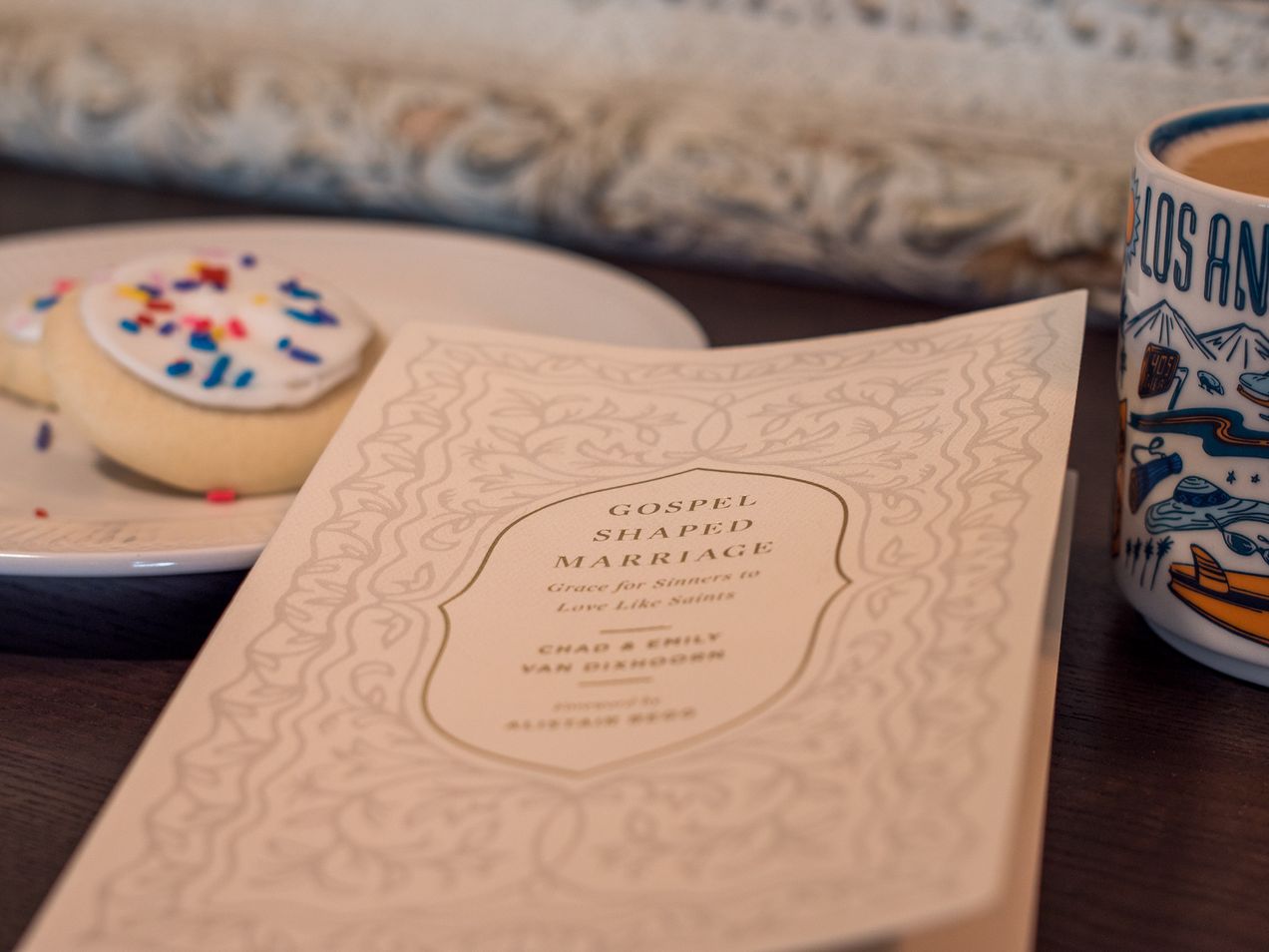 Photo of the book "Gospel-Shaped Marriage," a plate of cookies, and a Los Angeles coffee mug.