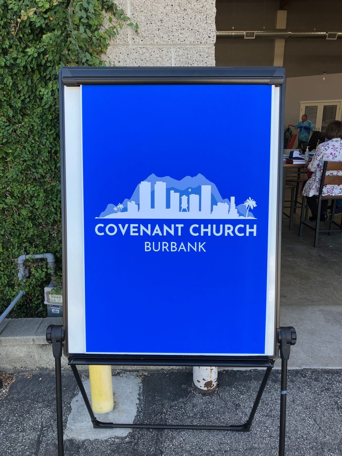 People gathering outside the Covenant Church sign in Burbank before a Sunday worship service.