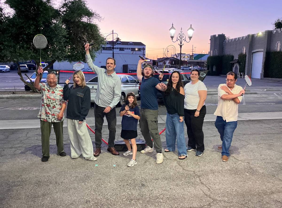 Members of Covenant Church — children and adults together — smiling with badminton rackets in hand at golden hour after an evening of fellowship in Burbank.